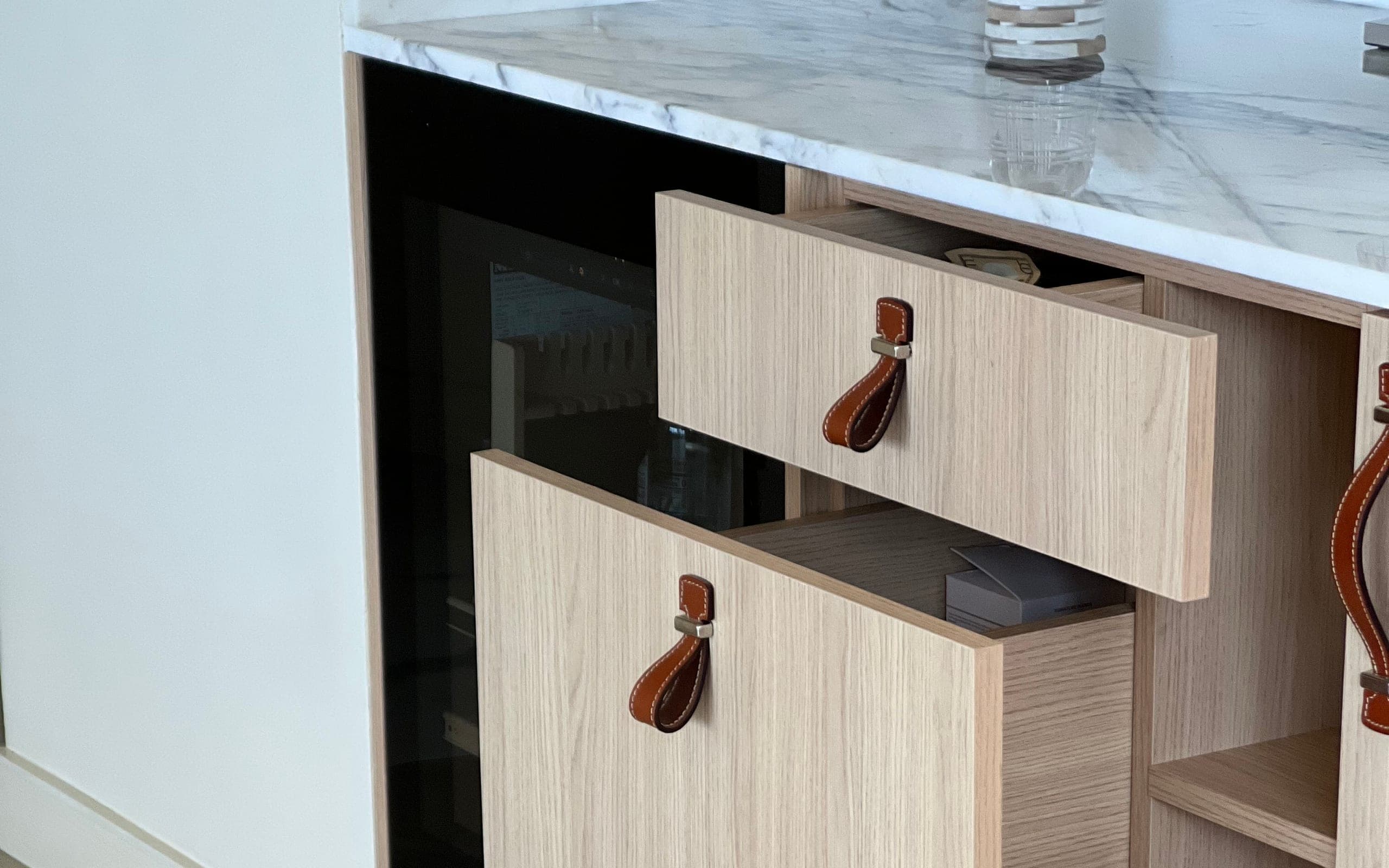 Oak drawers with stitched-leather pulls beneath a Calacatta marble countertop