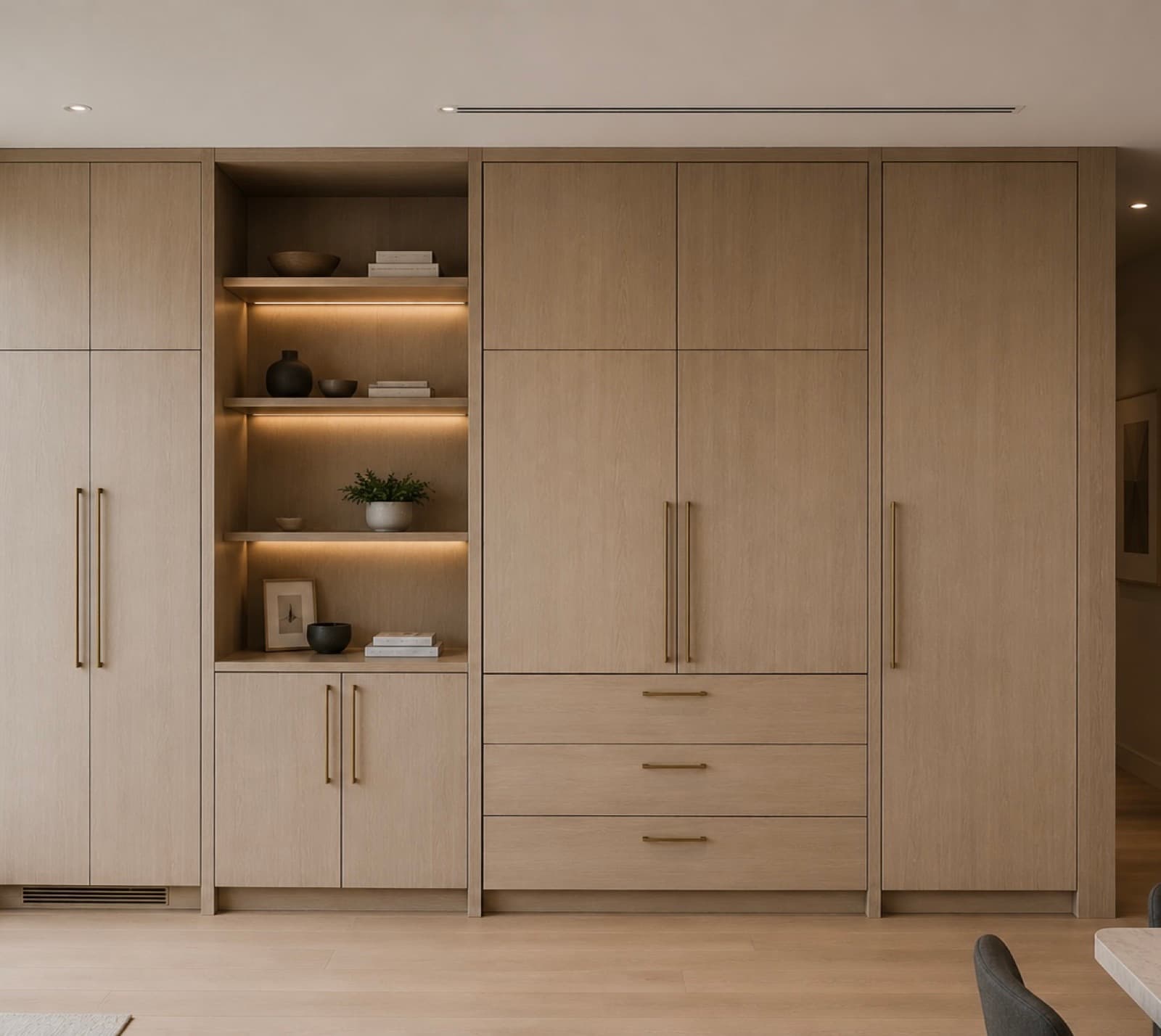 Floor-to-ceiling light-wood built-in wall with open shelving niche and brushed-brass pulls