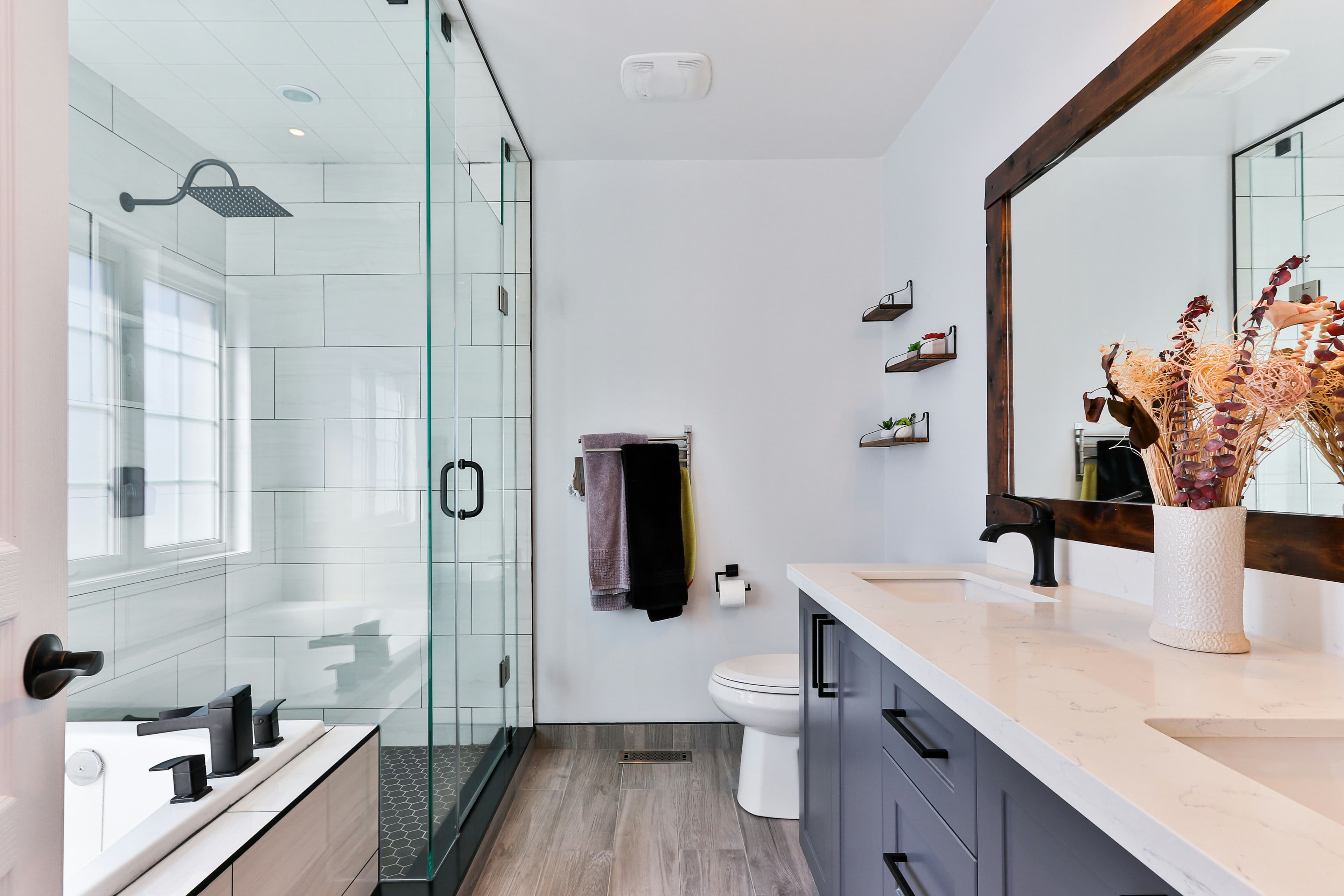 Modern bathroom with a long double vanity, stone countertop, framed mirror, and glass walk-in shower